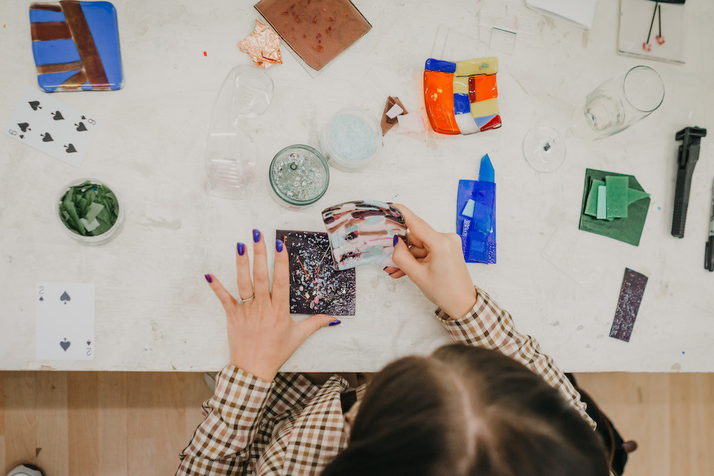 Overhead shot of a person sitting at a table arranging glass pieces for fusing